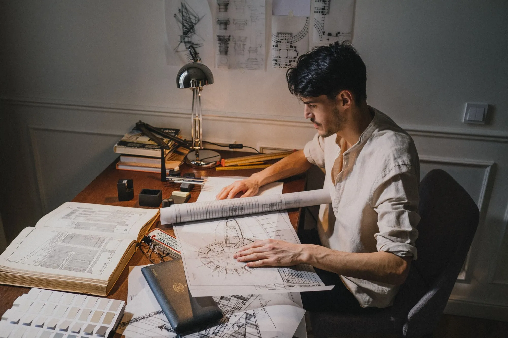 An architect comparing drawings and notes at a studio desk