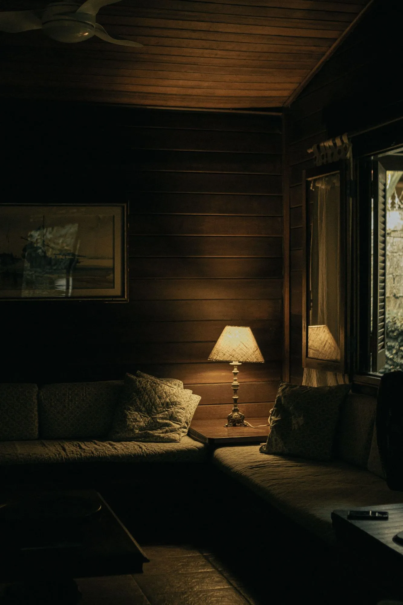 A softly lit timber-lined bedroom with a bedside lamp