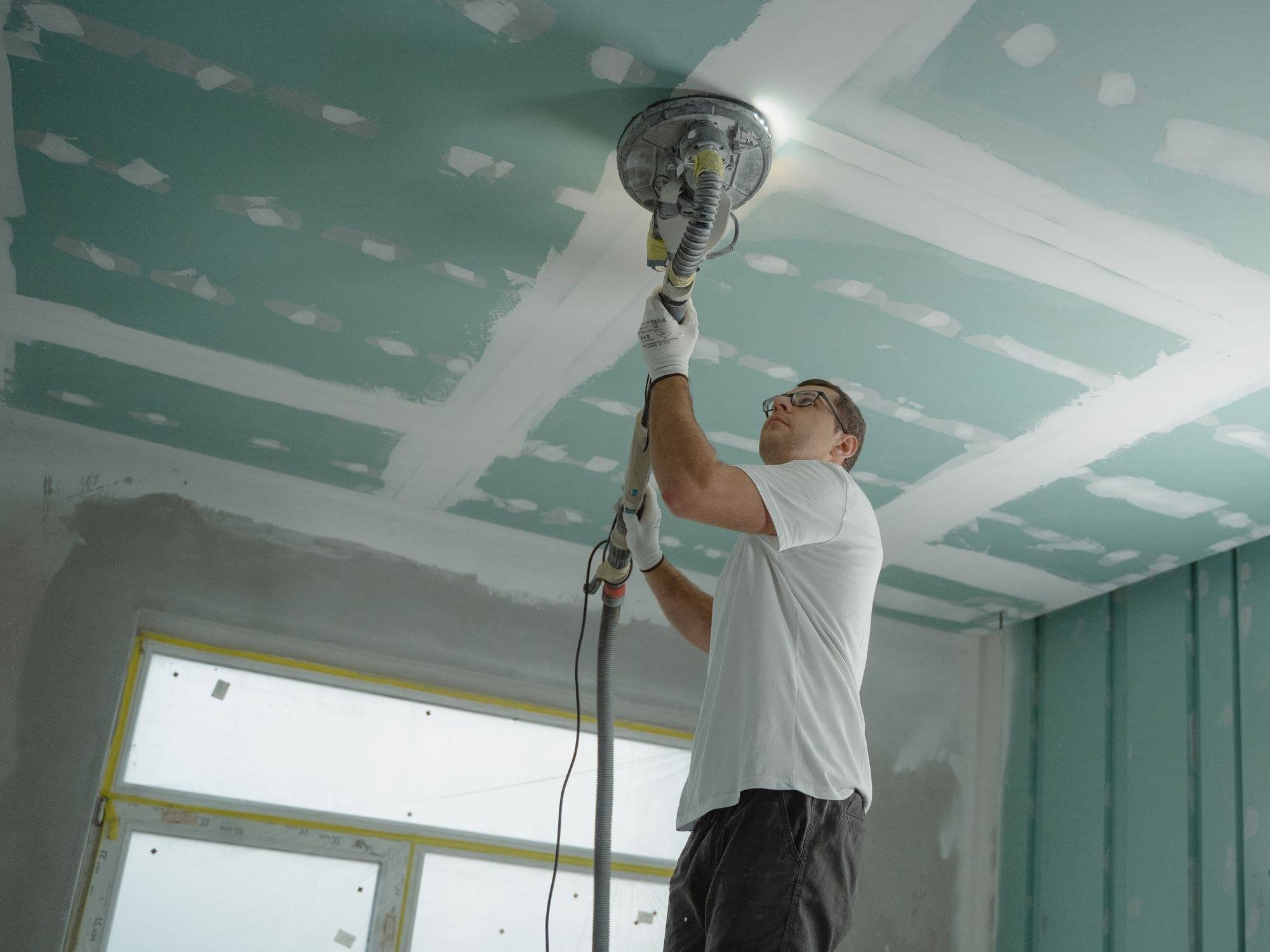 A worker finishing a plasterboard ceiling