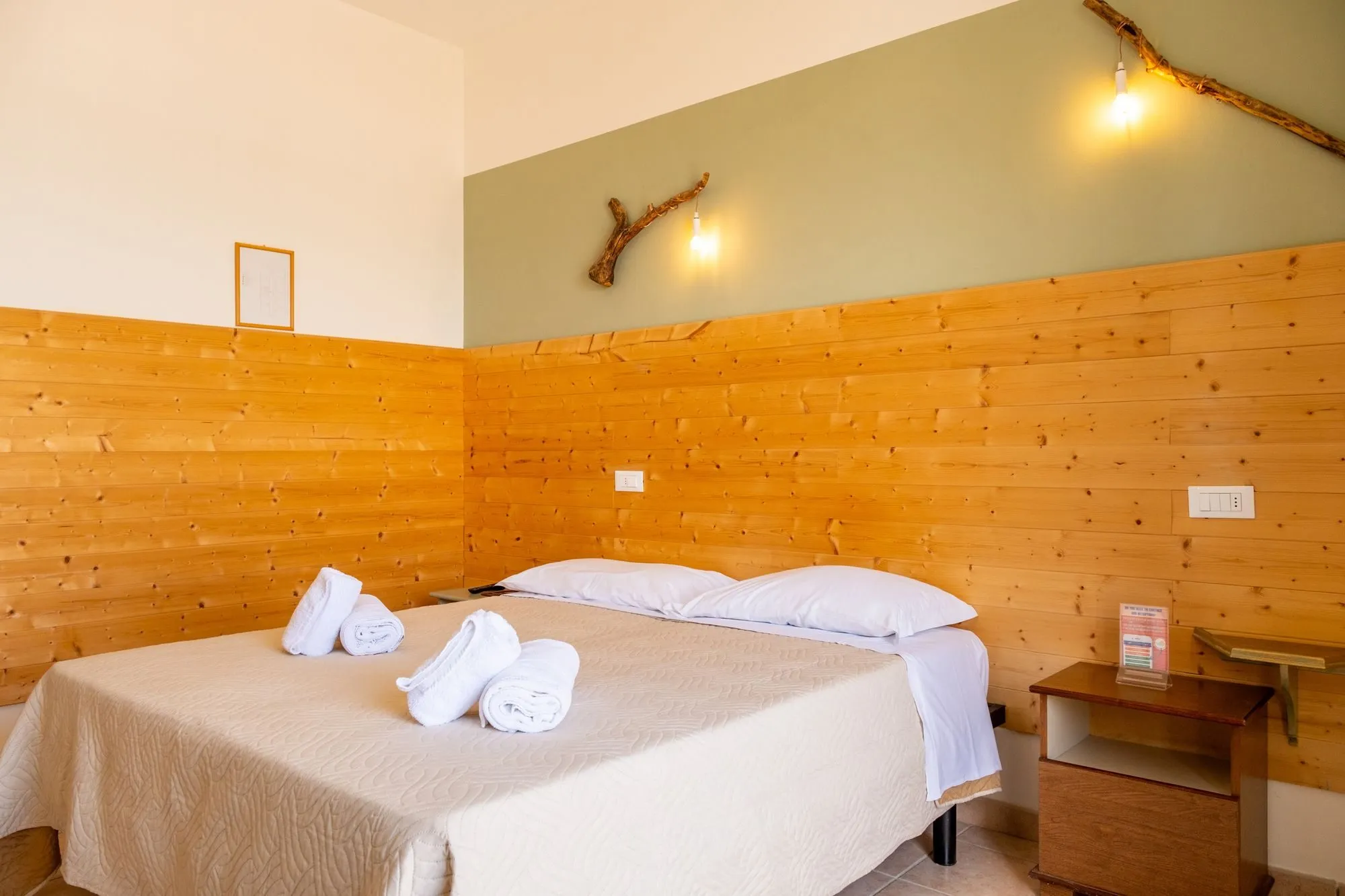A guest room with a double bed and timber-lined walls