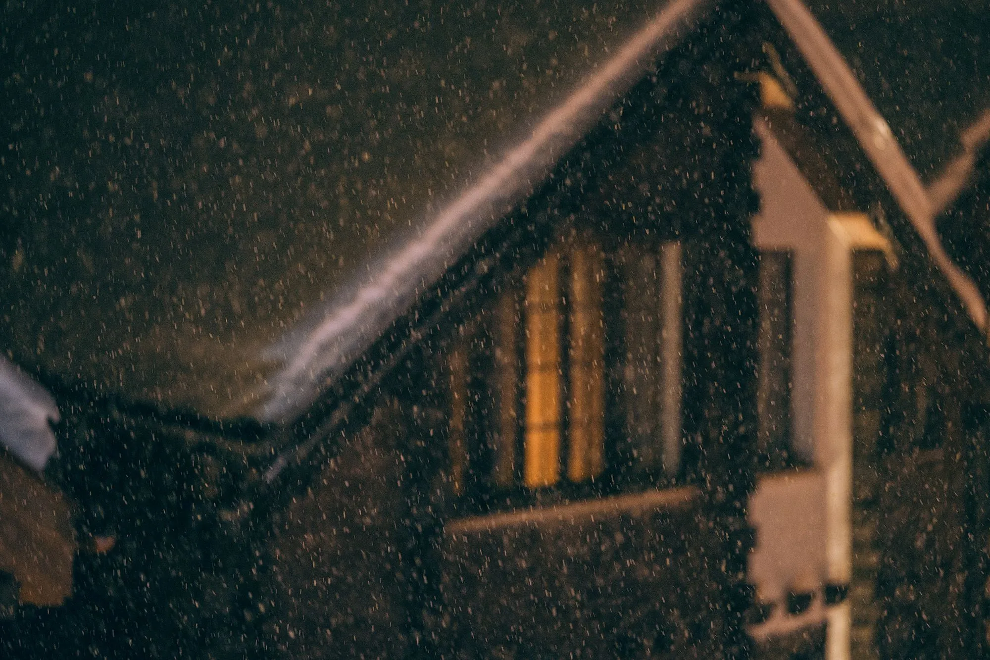 Large windows set within the timber facade of a house at night