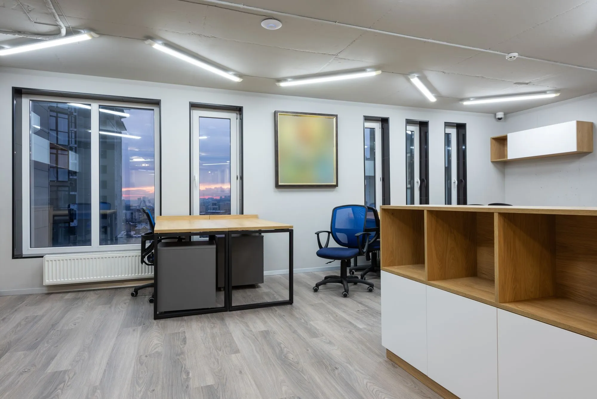 An occupied-space interior with desks, storage and large windows