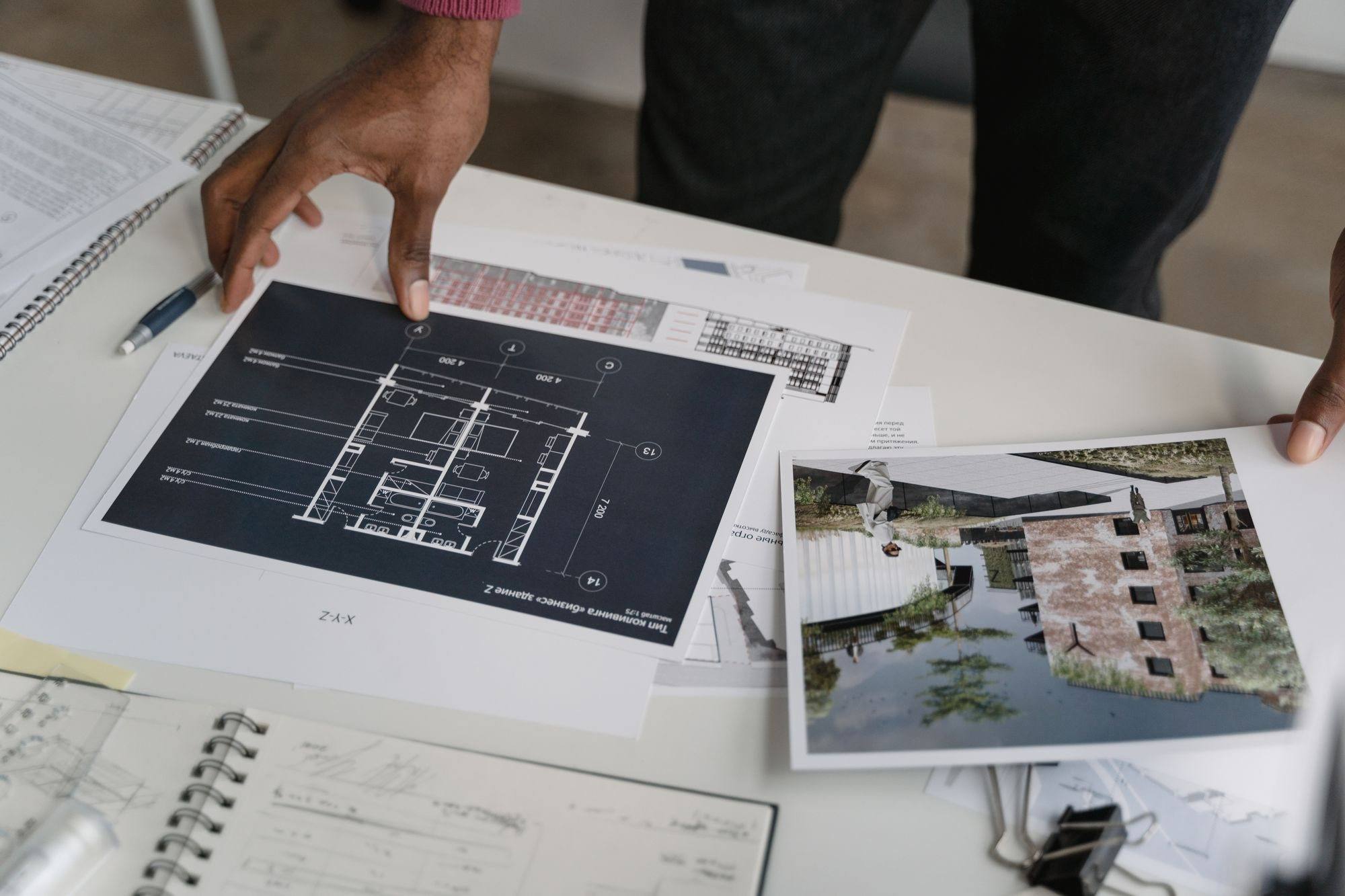 A person reviewing a printed plan and project photographs