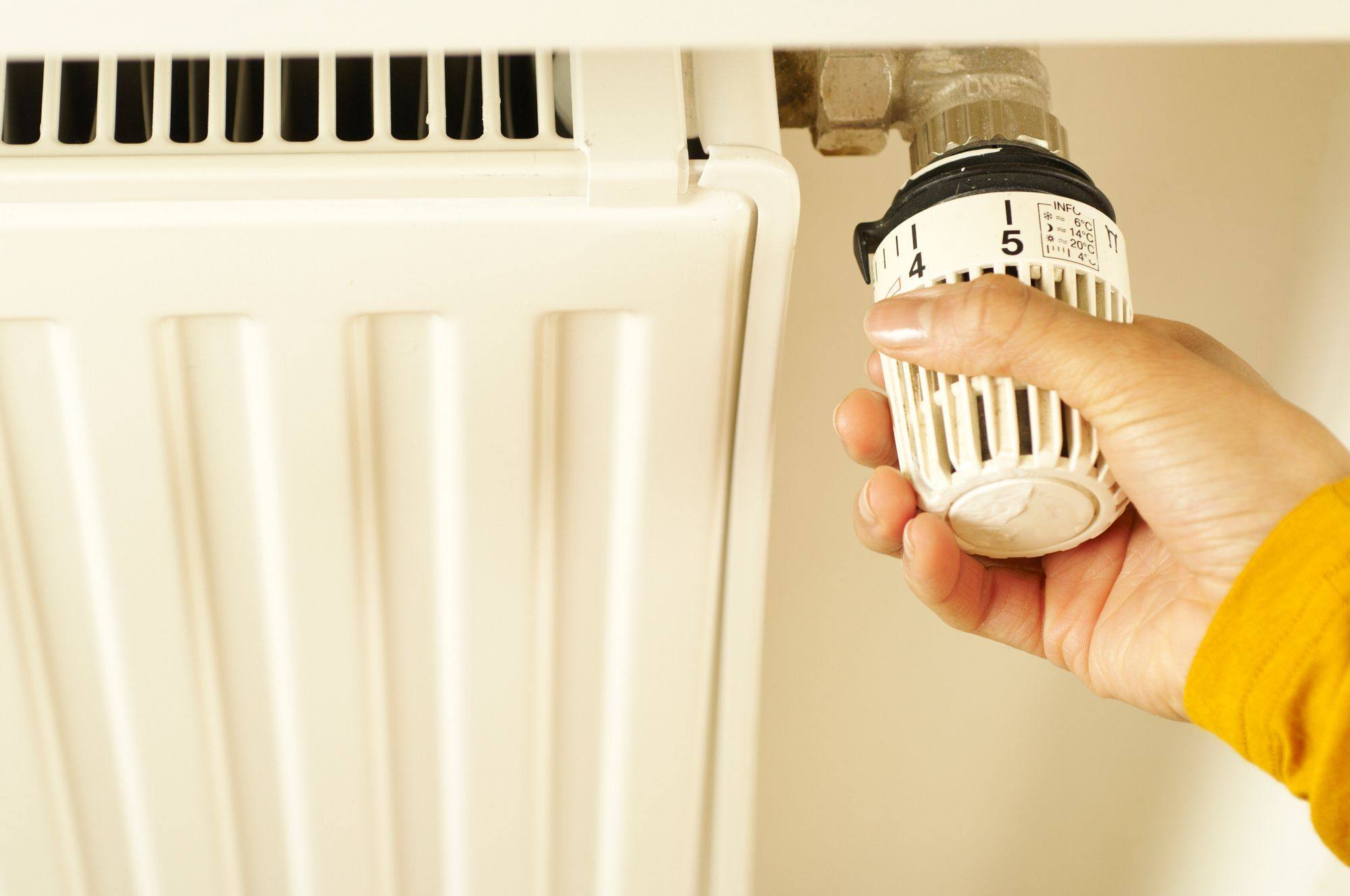 A hand adjusting a radiator temperature control