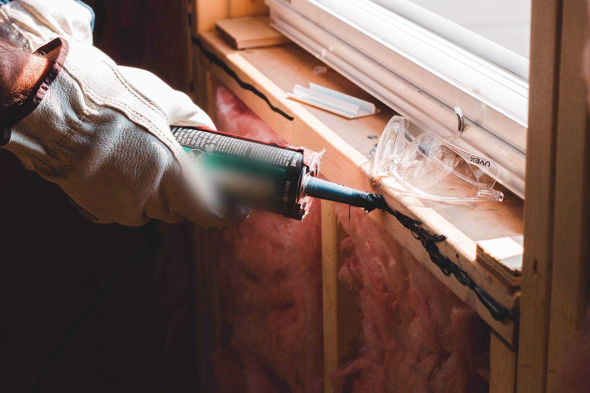 A window frame being sealed against the wall