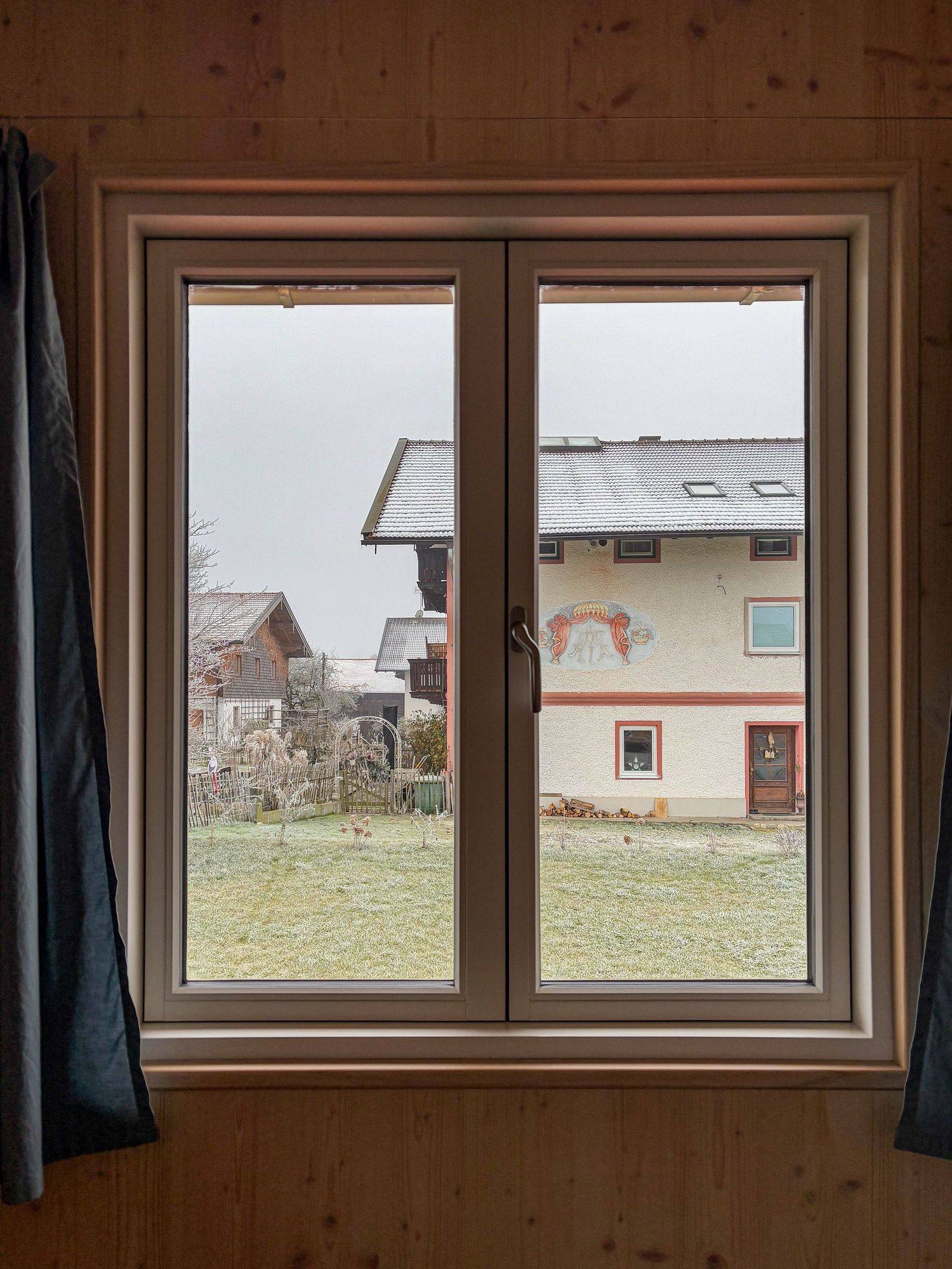 A timber-framed window looking towards a neighbouring house